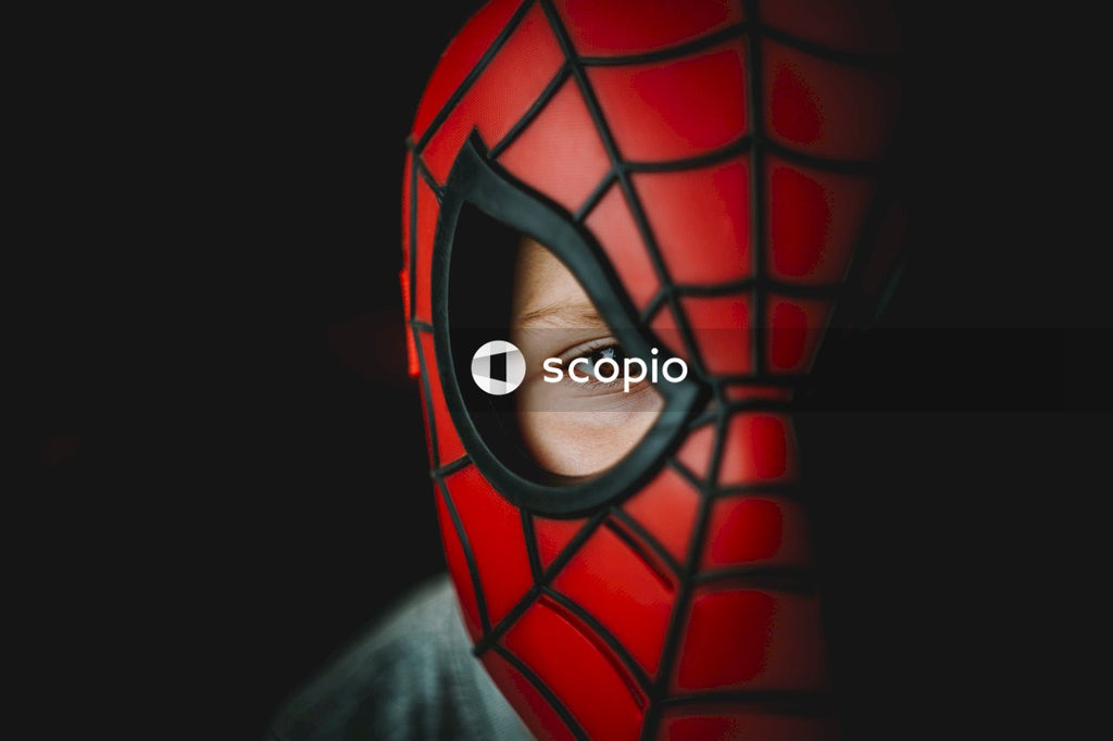 Eye of a boy under a red and black spider man mask