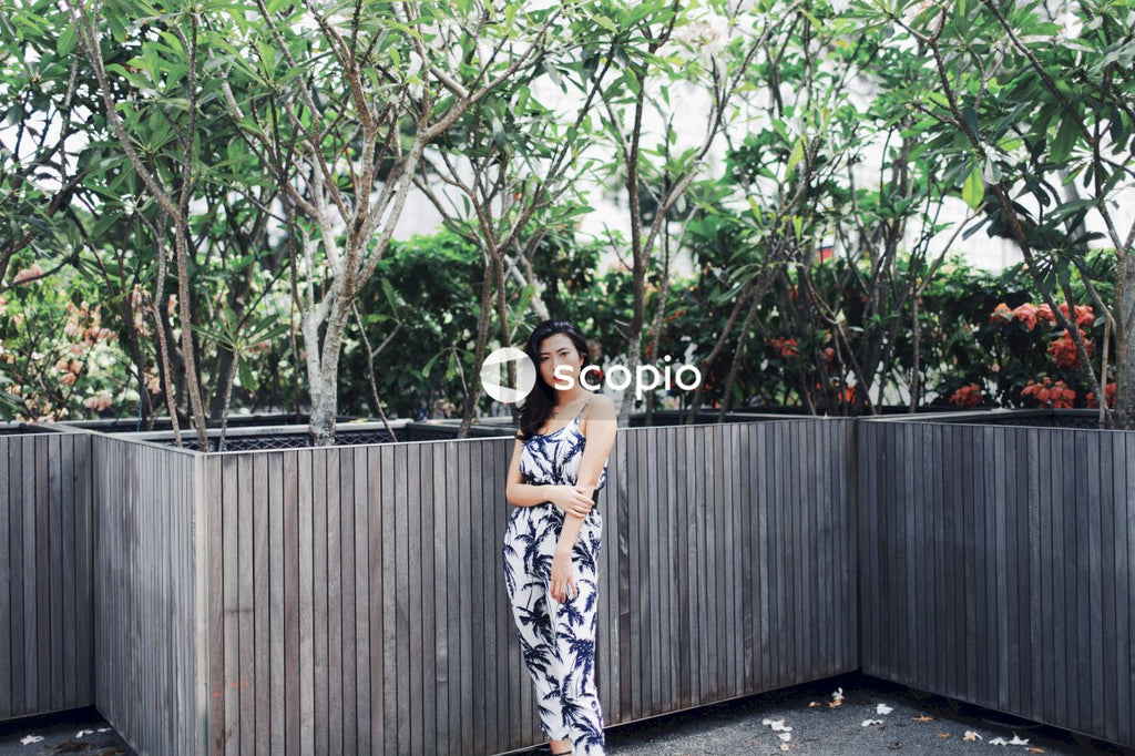 Woman wearing jumpsuit near flower bushes