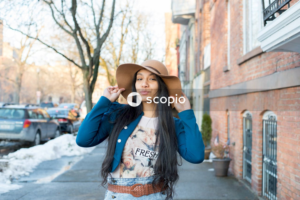 Woman wearing fedora hat standing on sidewalk