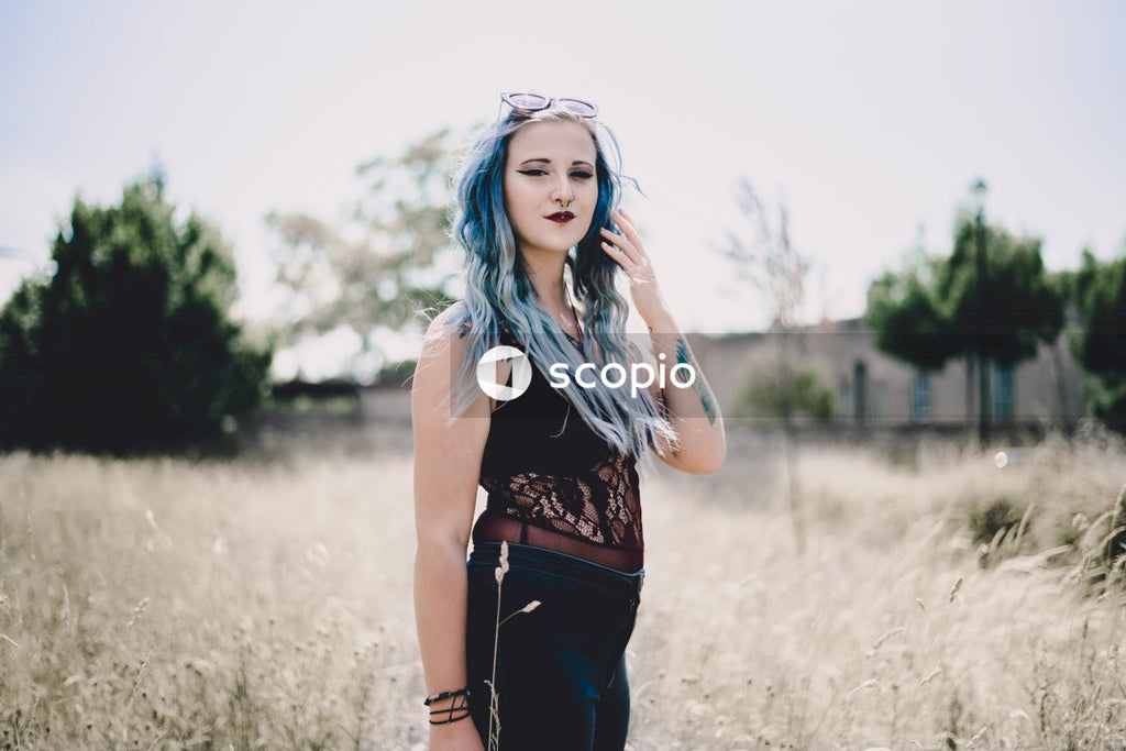 Woman in black tank top and black pants standing on brown grass field