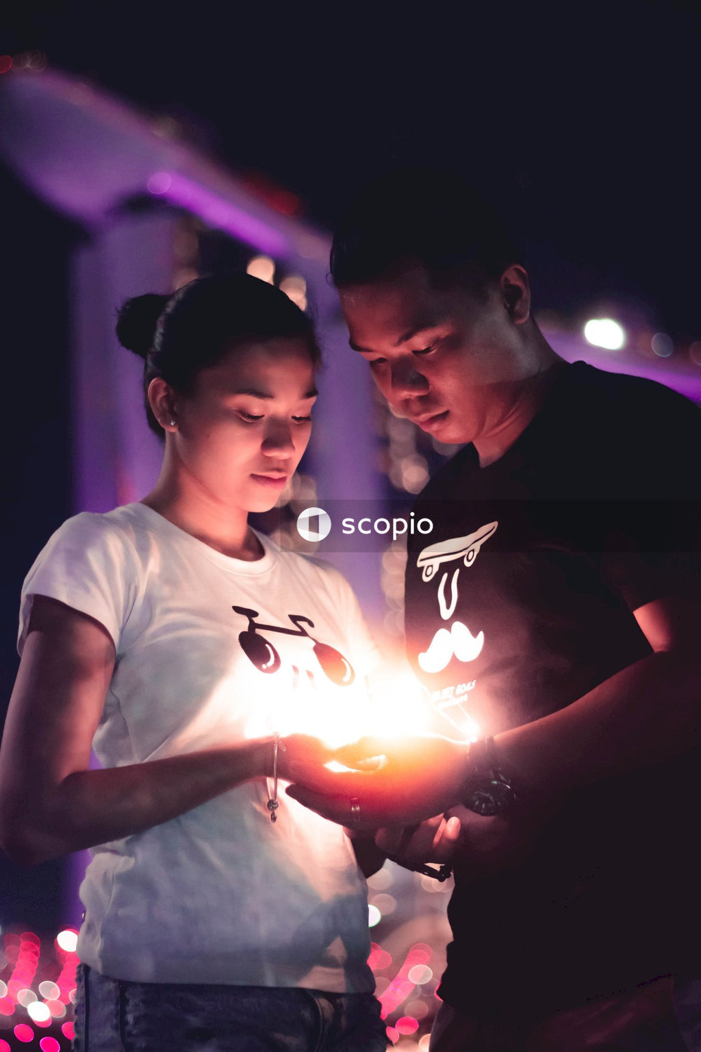Man and woman holding lighted candle at night