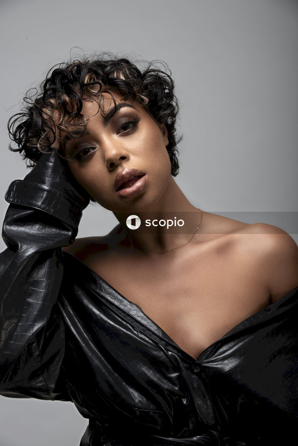 Woman in off shoulder leather top and short hair holding her head