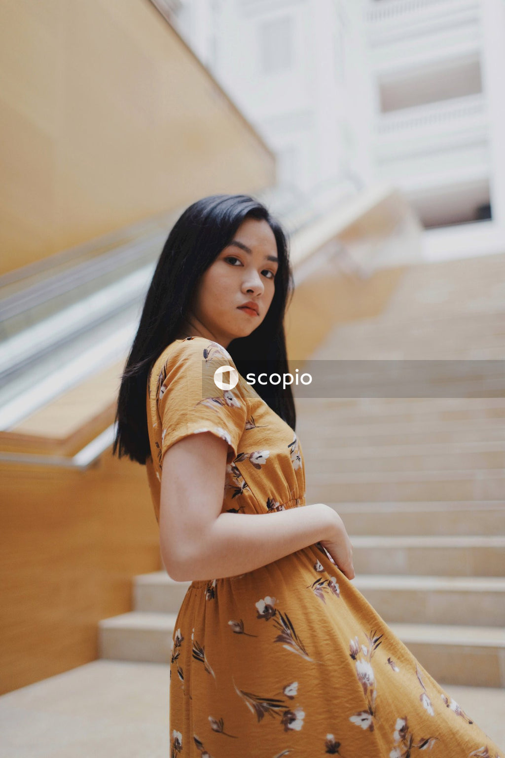 Asian woman in orange dress standing on stairs