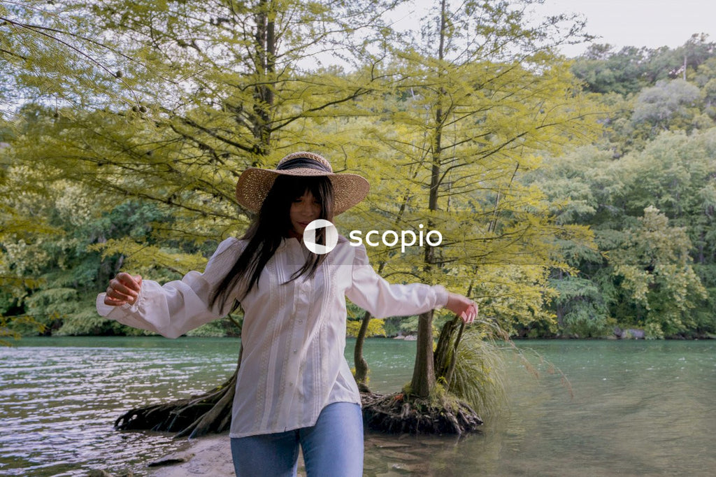 Woman in white long sleeve shirt and blue denim jeans standing on body of water