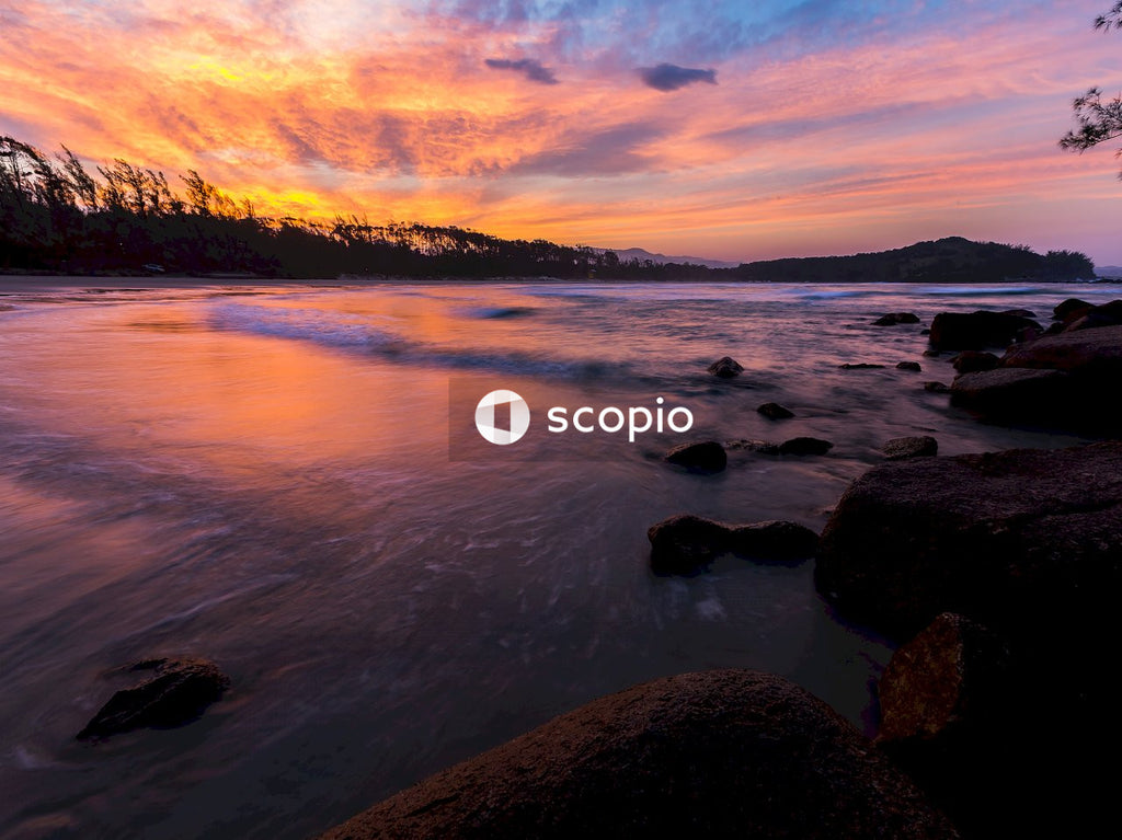 Body of water near rocks during sunset