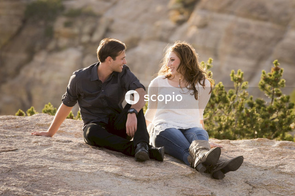Young man and woman sitting on rock formation outdoor