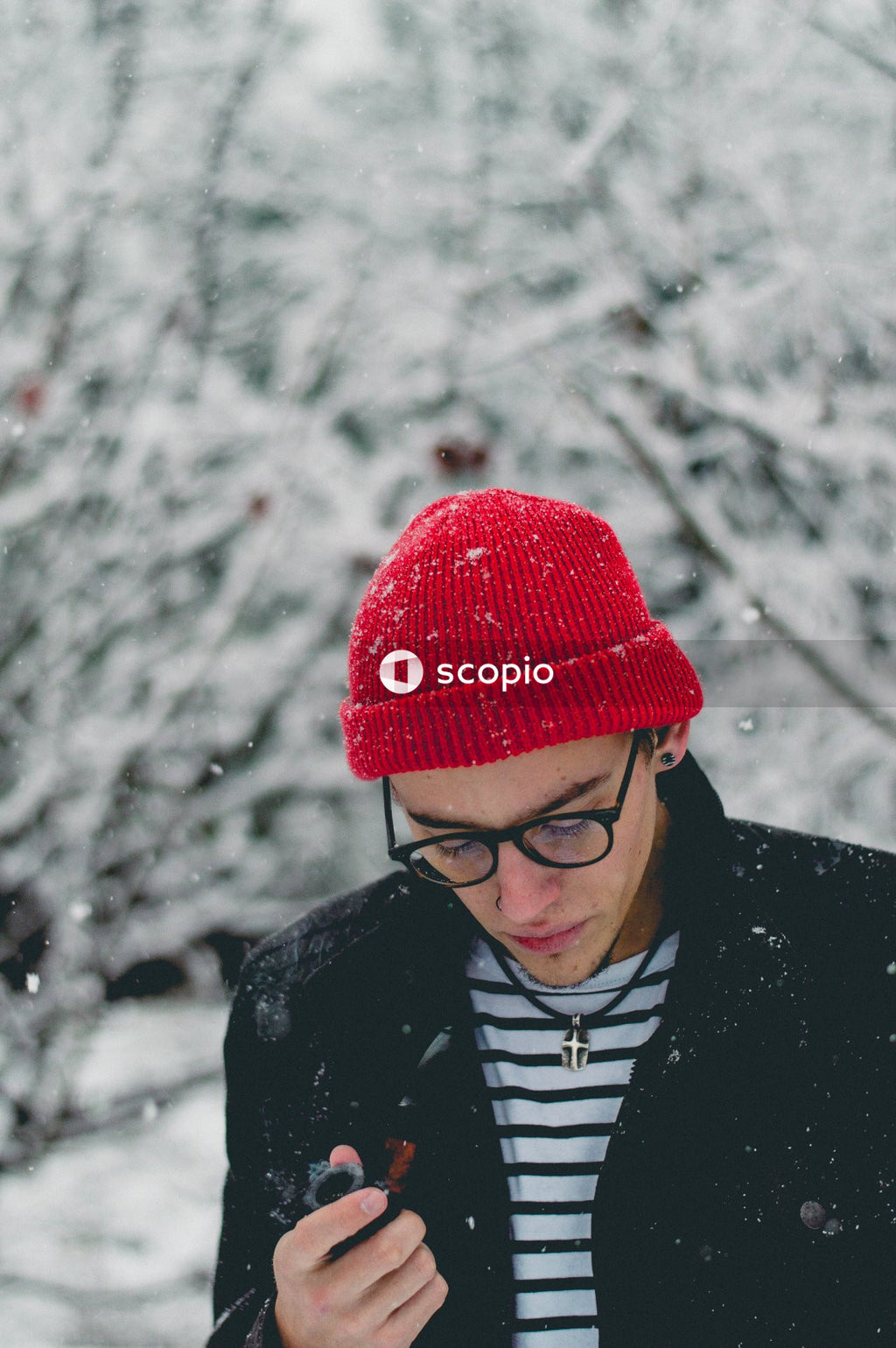 Man in black jacket wearing red knit cap and eyeglasses