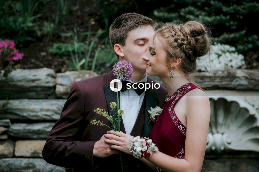 Man in black suit kissing woman in white floral dress
