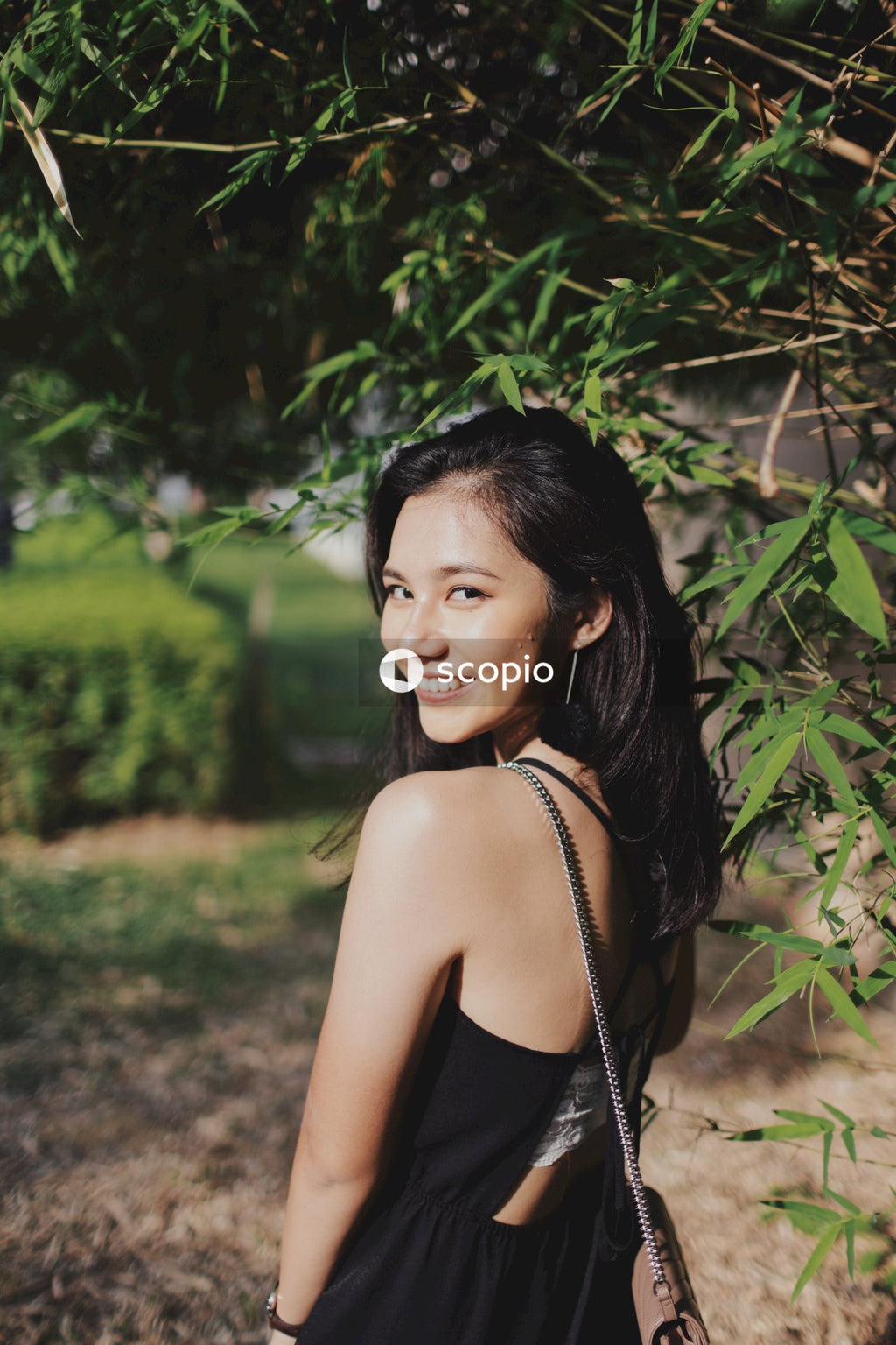 Woman in dark dress posing near flowers bushes