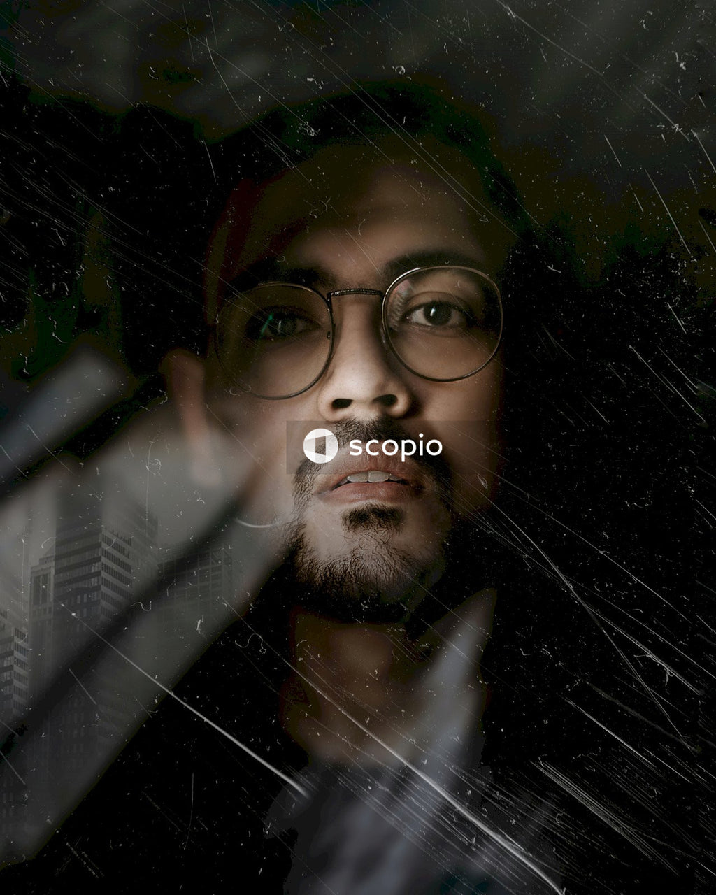 Man with mustache wearing round eyeglasses standing behind window
