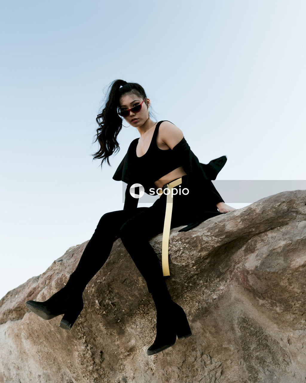 Woman in dark outfit posing on rock