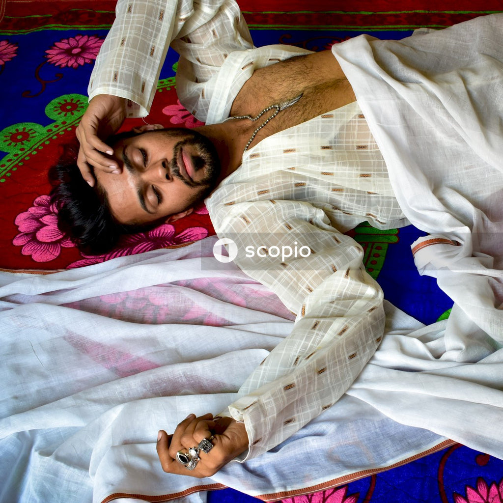 Man in white long-sleeved shirt lying on bed