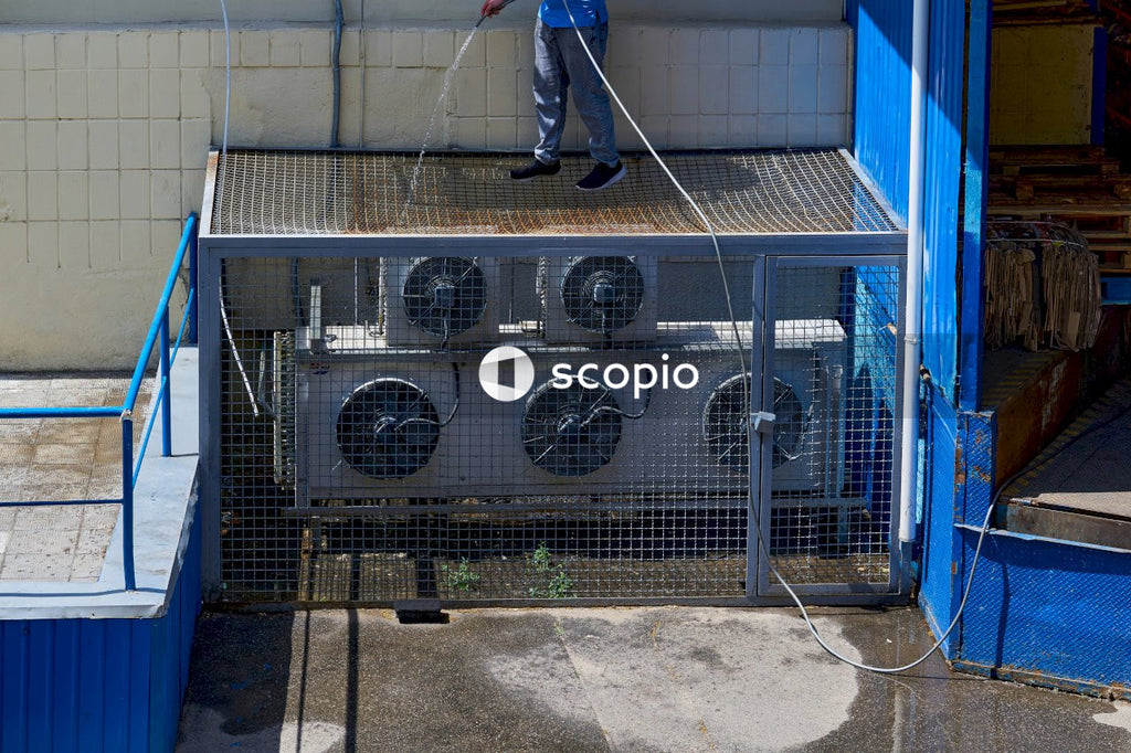 A worker washes cleans the air conditioning system in the backyard of a factory