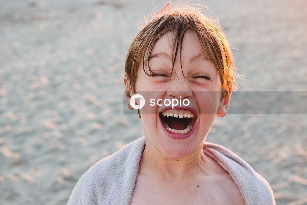 Young blond boy with wet hair smiling at the beach