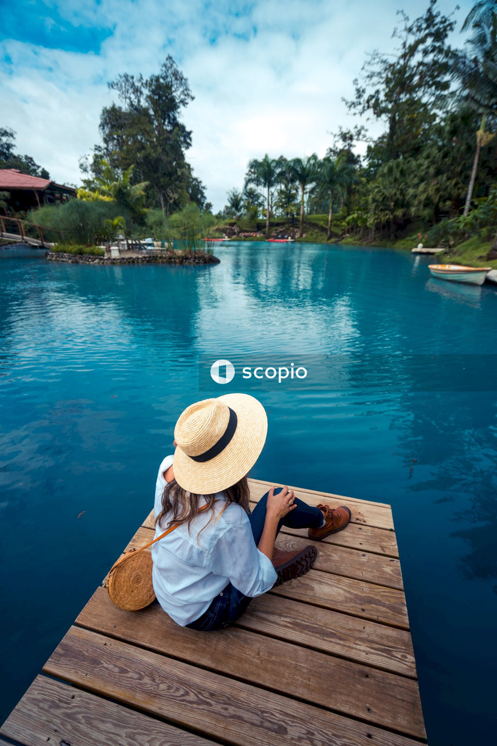 Woman sitting on wooden dock beside river