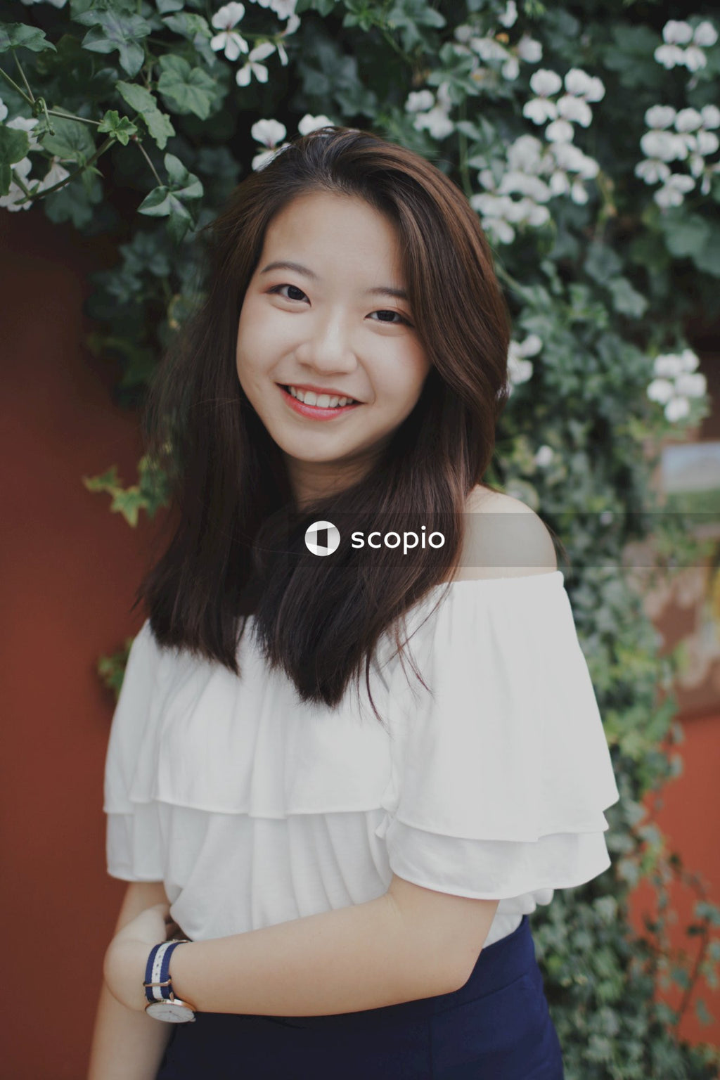 Asian woman posing in front of flowers bushes