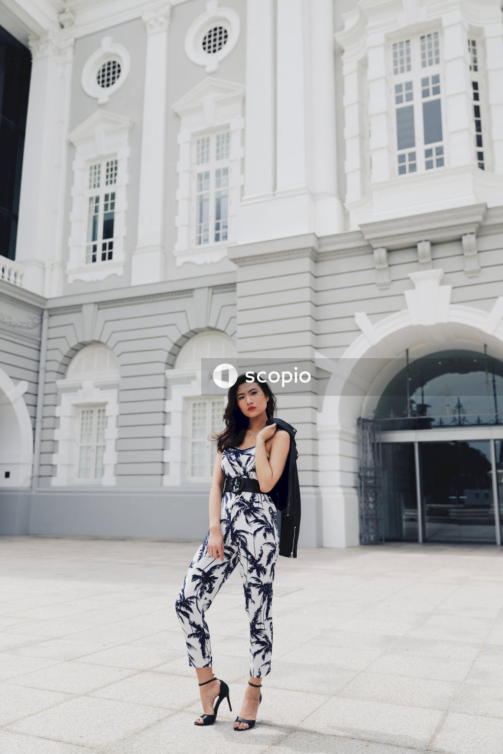 Woman in Grey Floral Dress Standing in Front of Large Building