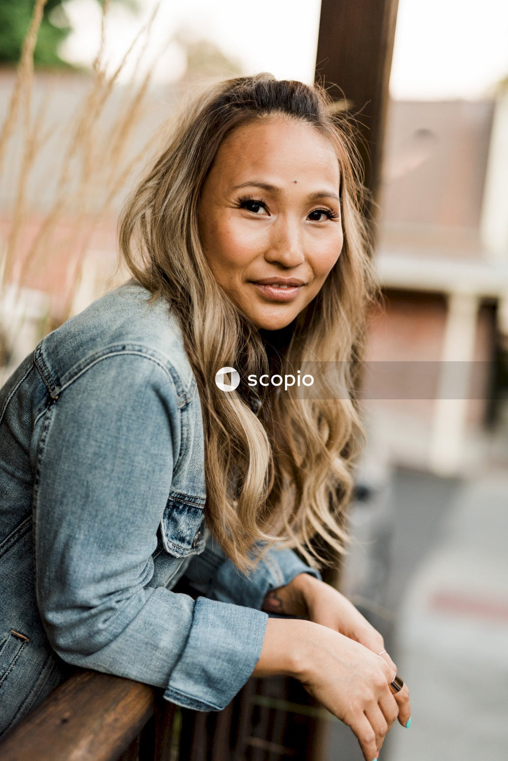 Portrait of woman smiling and standing beside wooden rail