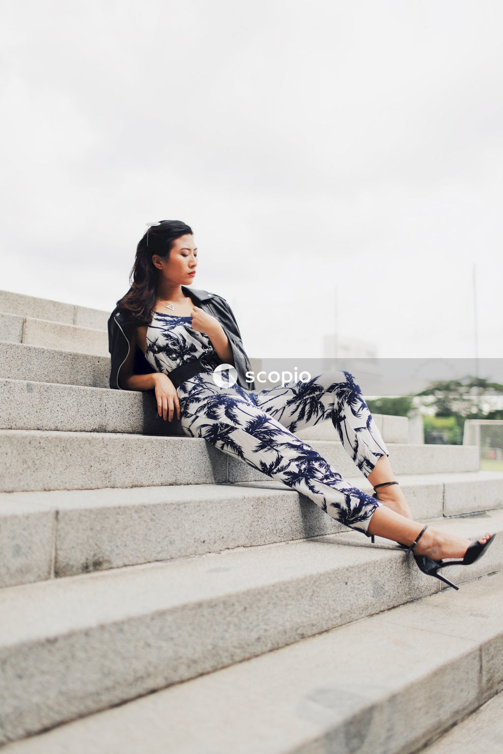 Woman in light and dark jumpsuit posing in front of building
