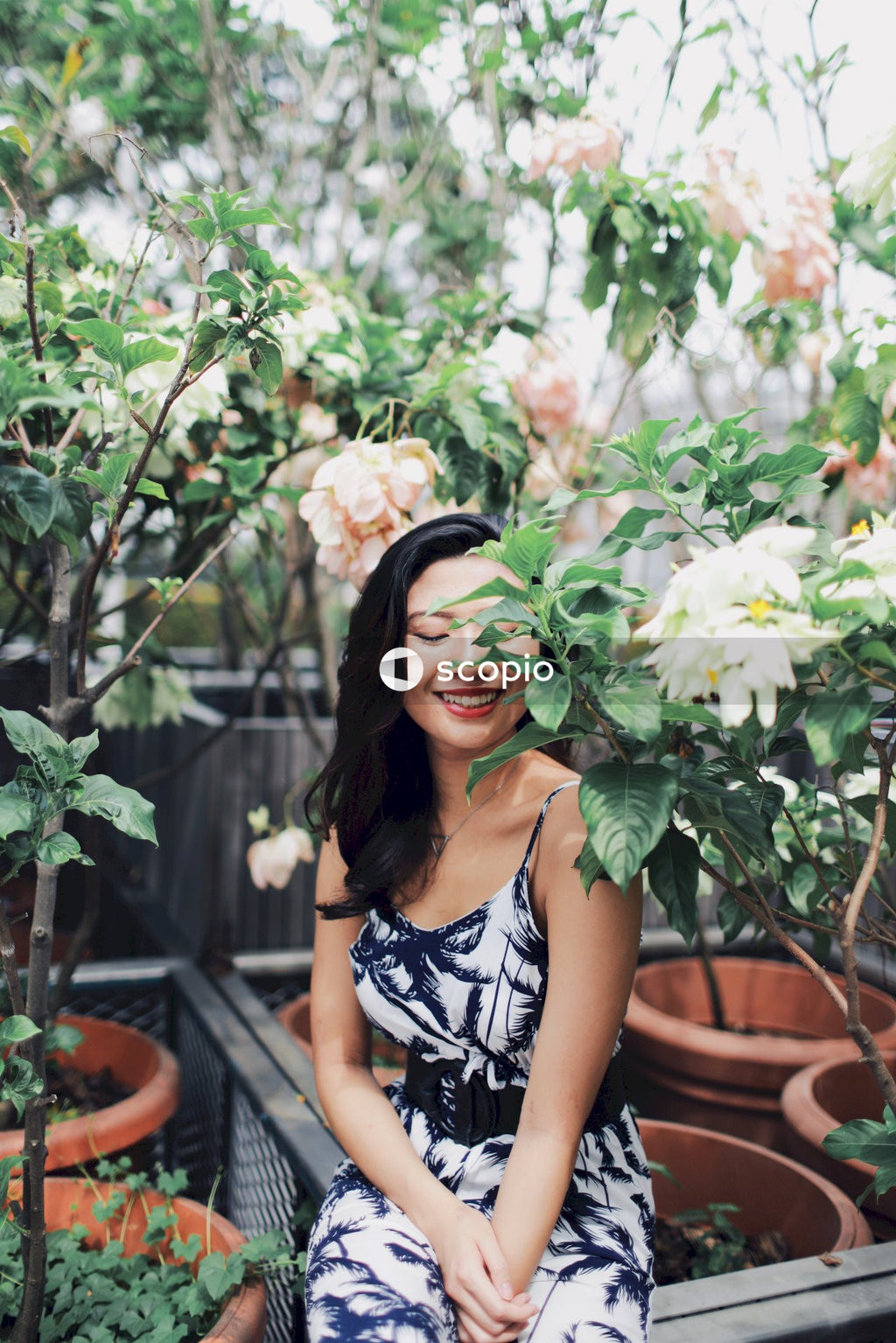Woman wearing jumpsuit near flower bushes