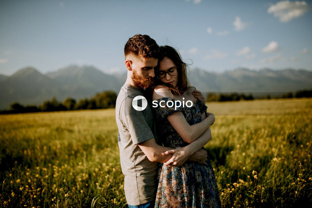 Man and woman hugging in green grass field