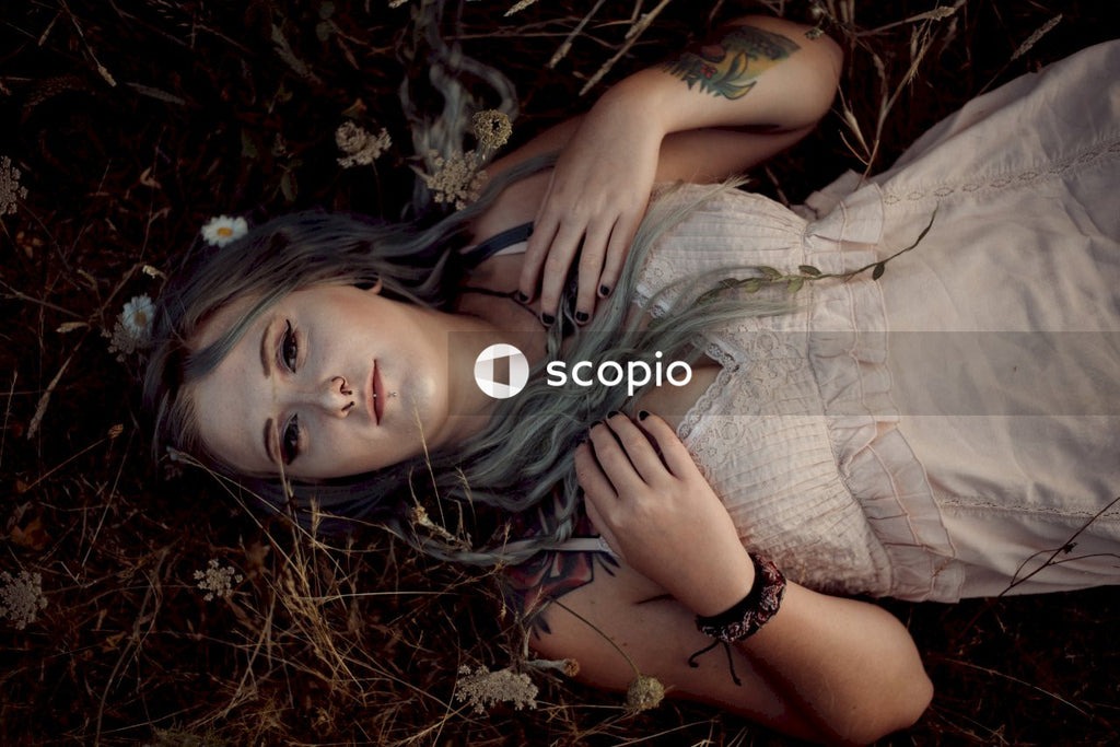 Woman in brown and white plaid dress lying on brown dried leaves