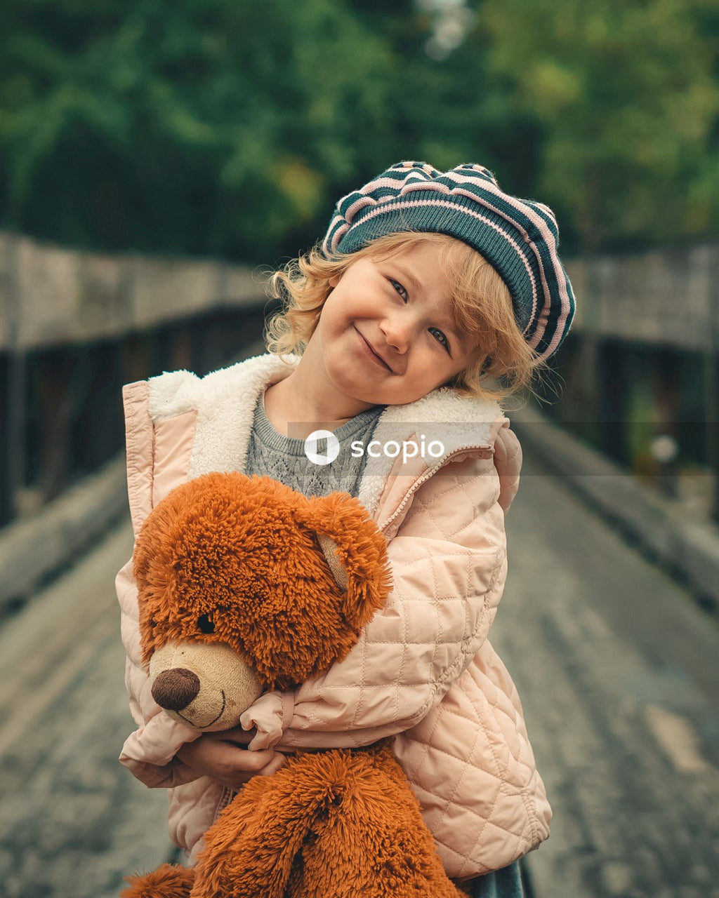 Girl in white jacket hugging brown bear plush toy