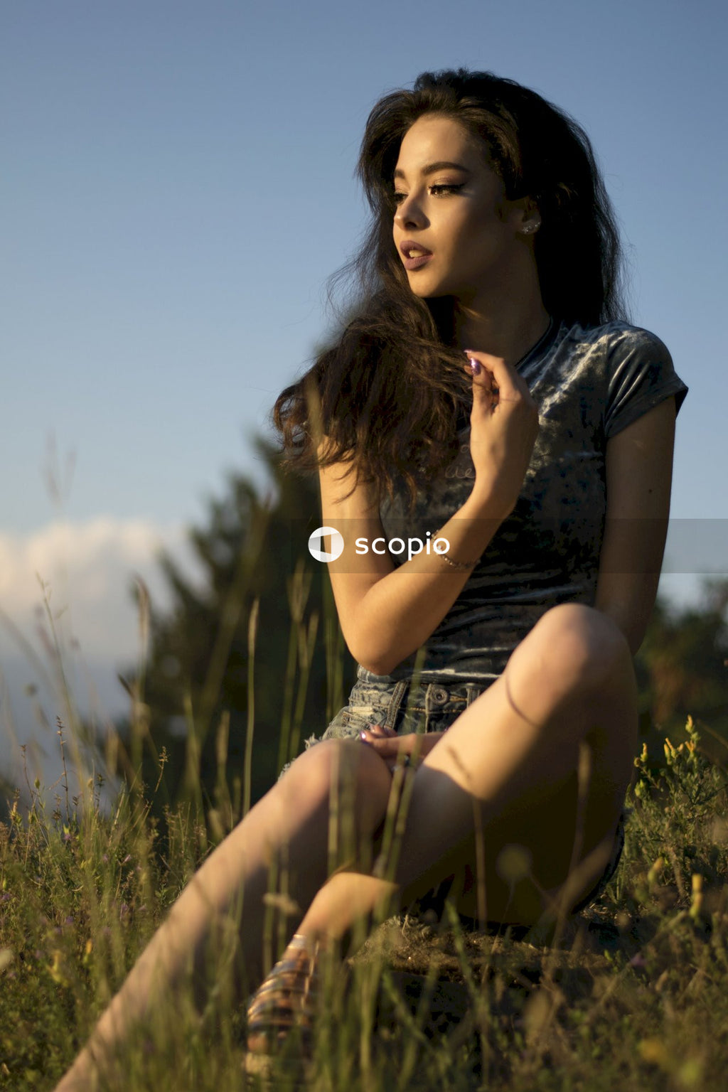 Woman in gray top and shorts sitting on green grass