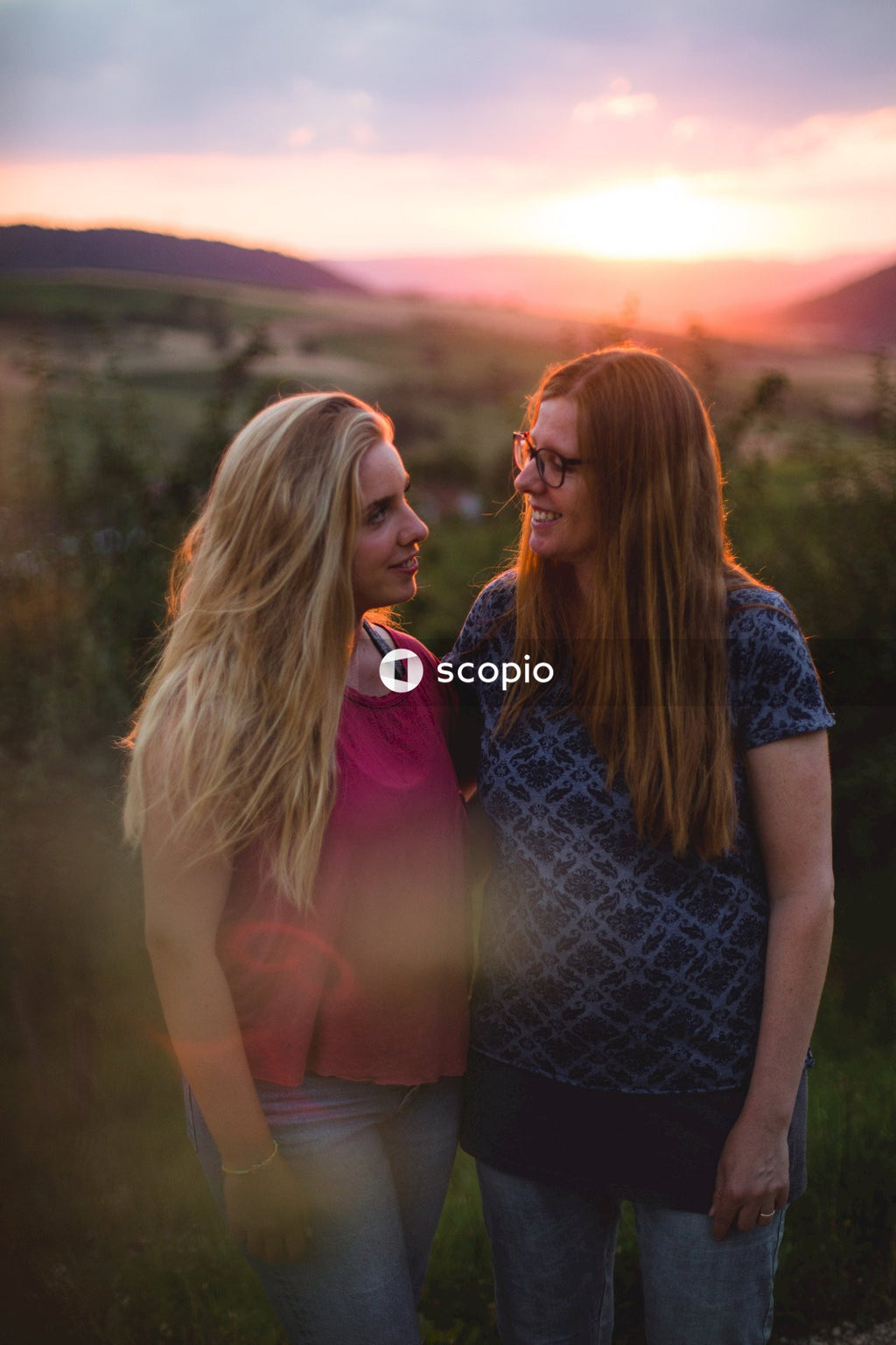 Woman in purple shirt hugging woman in blue shirt