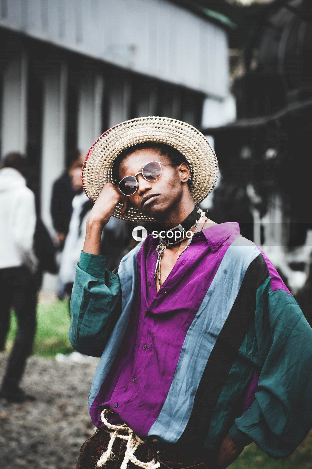 Man in purple and green top with brown hat posing outdoor