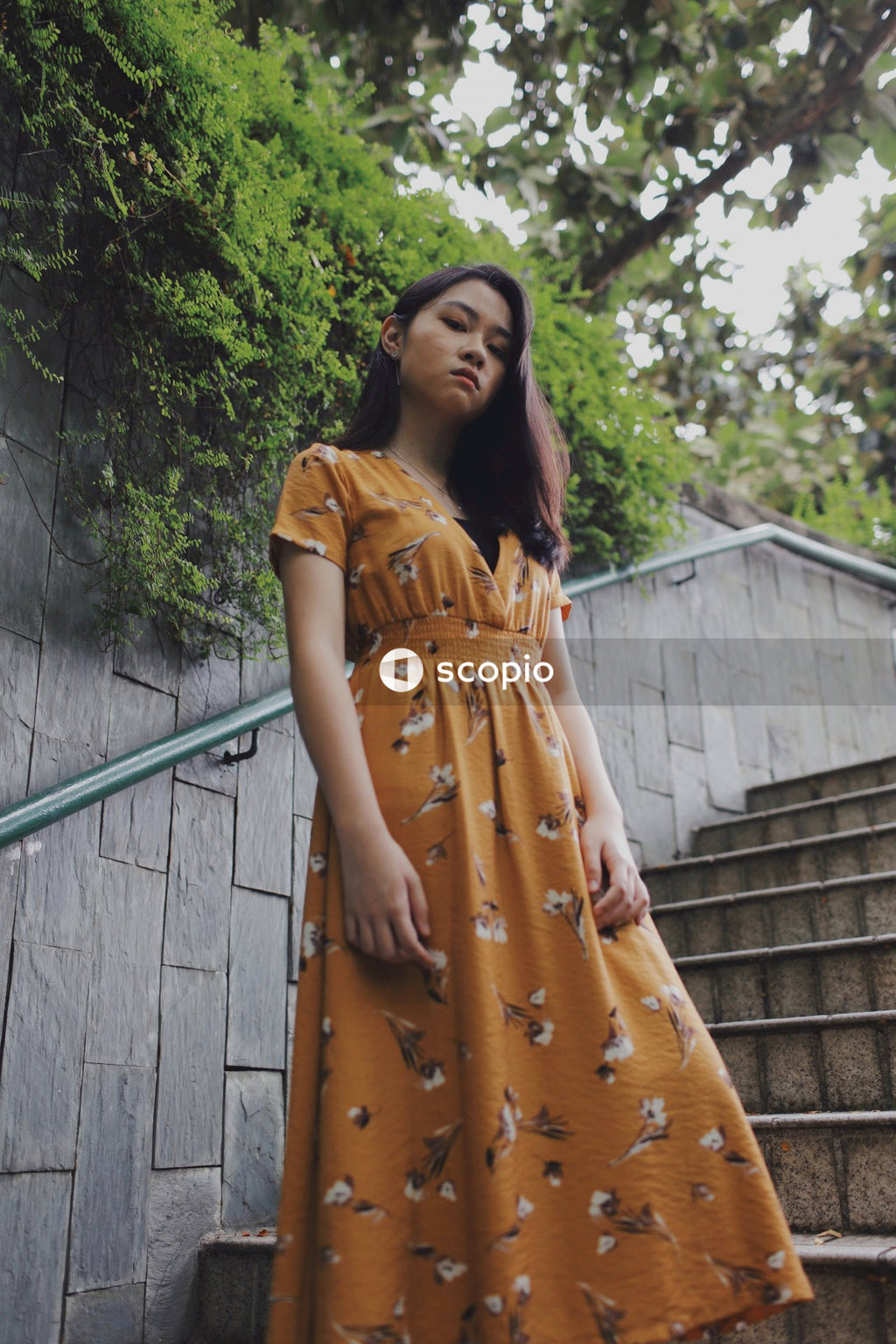 Asian woman in orange dress standing on stairs