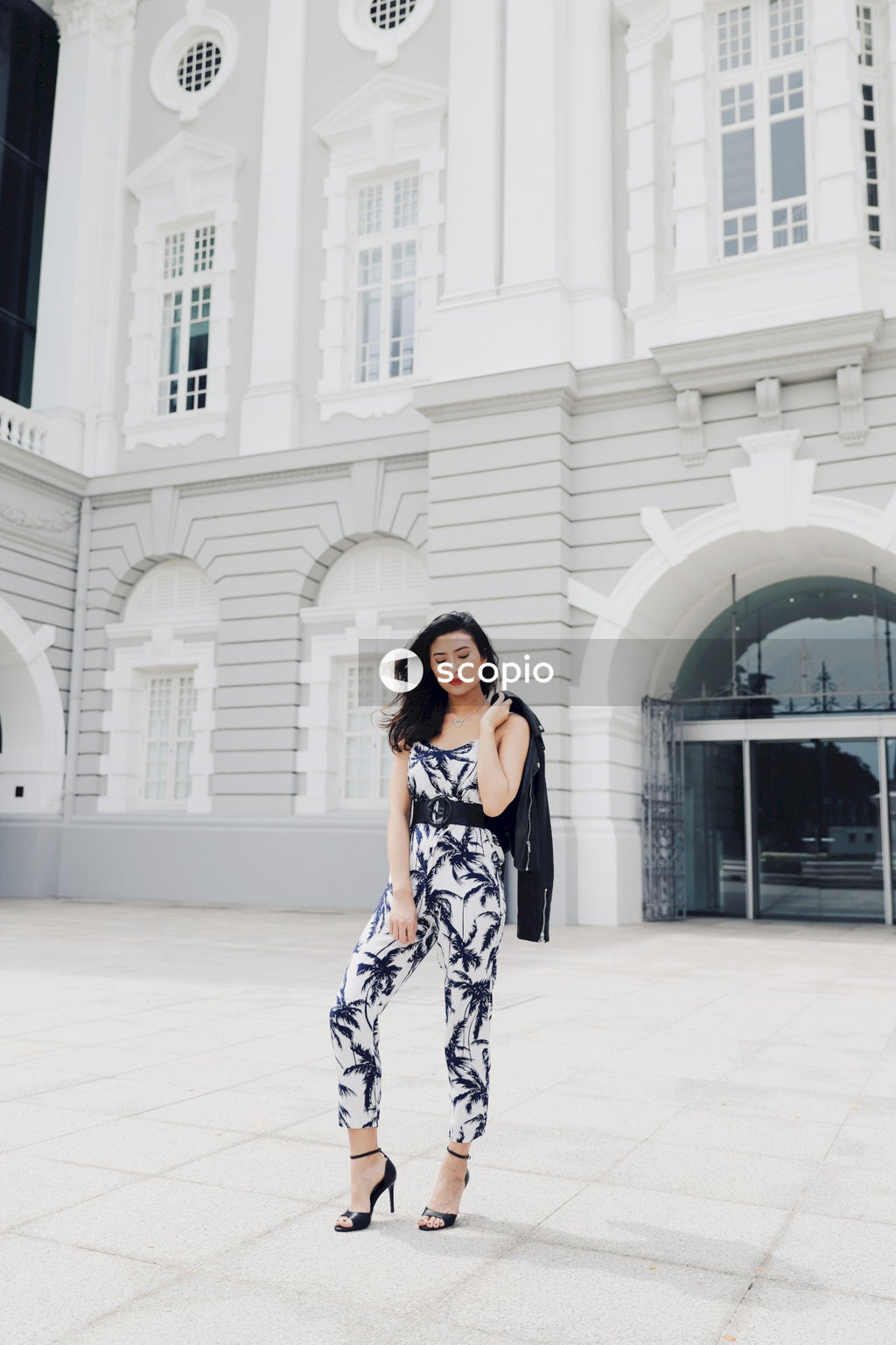 Woman in light and dark jumpsuit posing in front of building