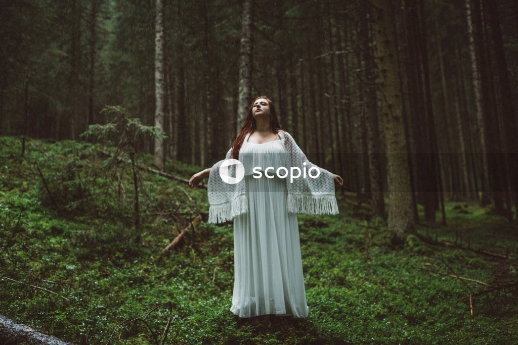 Woman wearing white dress in middle of forest