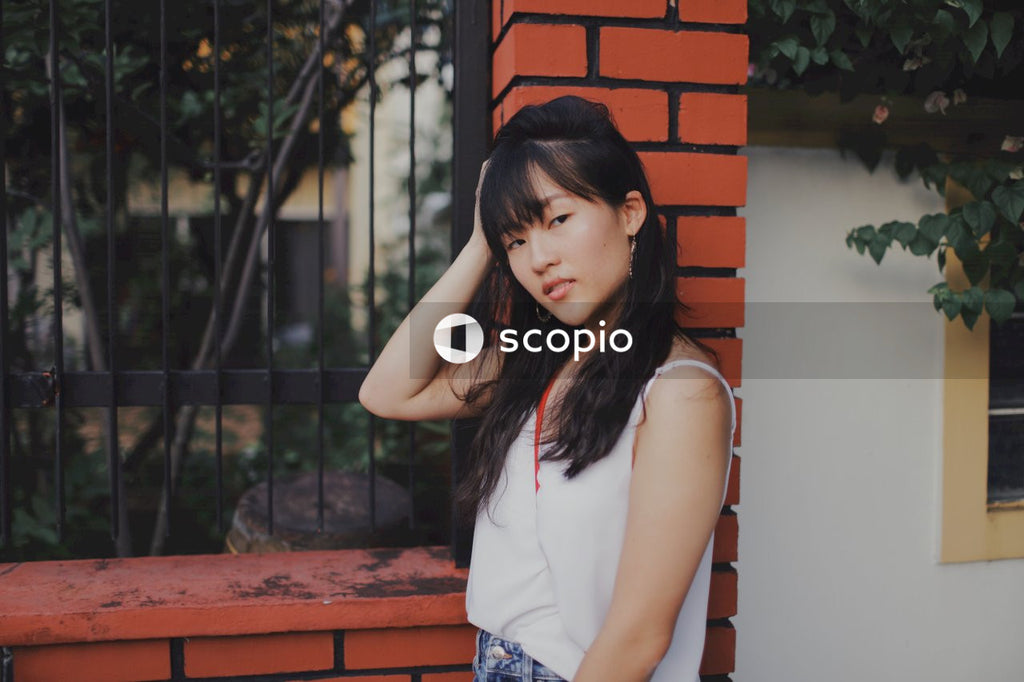 Woman wearing light top leaning on building pillar