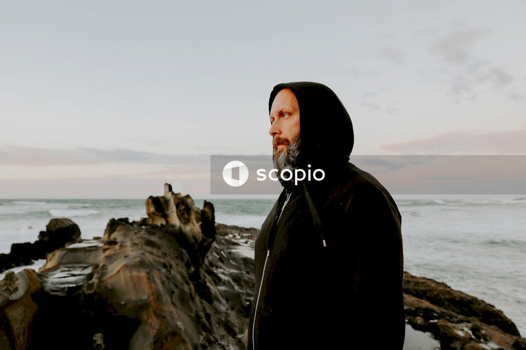 Man in black hoodie standing on rock formation