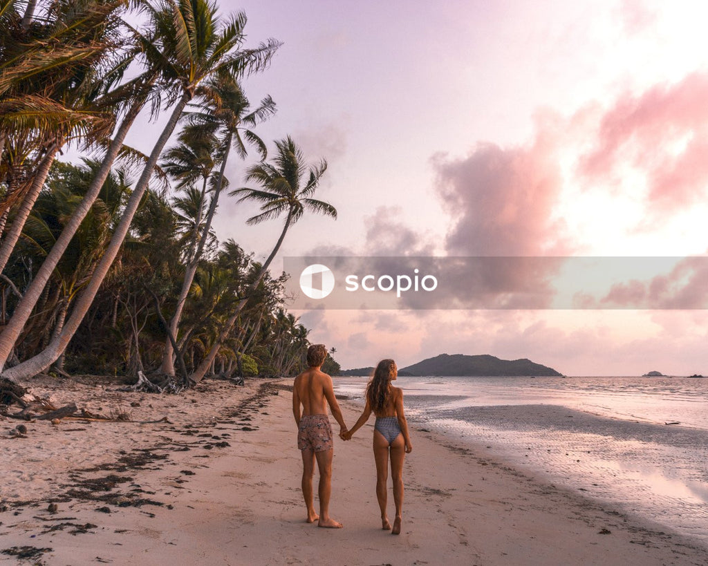 Man and Woman in brown bikini walking on beach