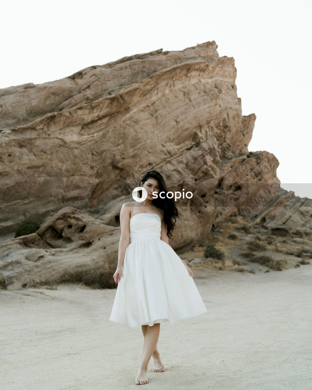 Woman in white tube dress standing on beach