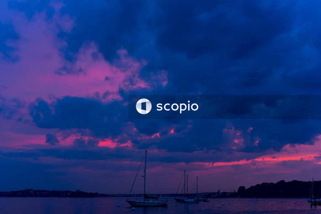 White sail boat on sea under cloudy sky during sunset