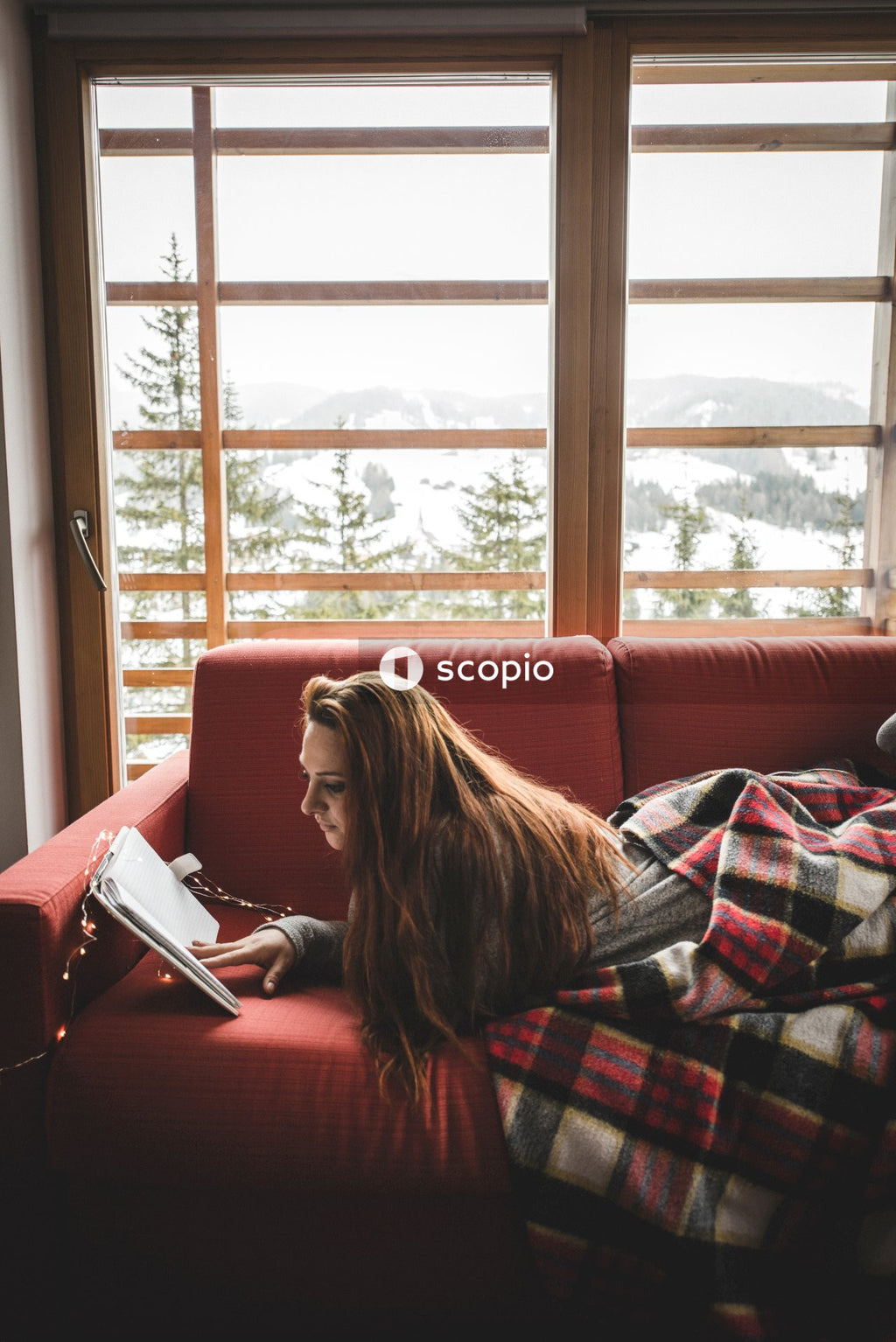 Woman laying on sofa reading a book