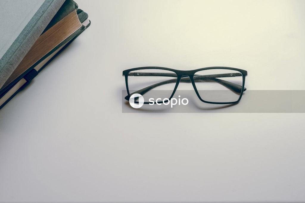 Eyeglasses next to books on white table