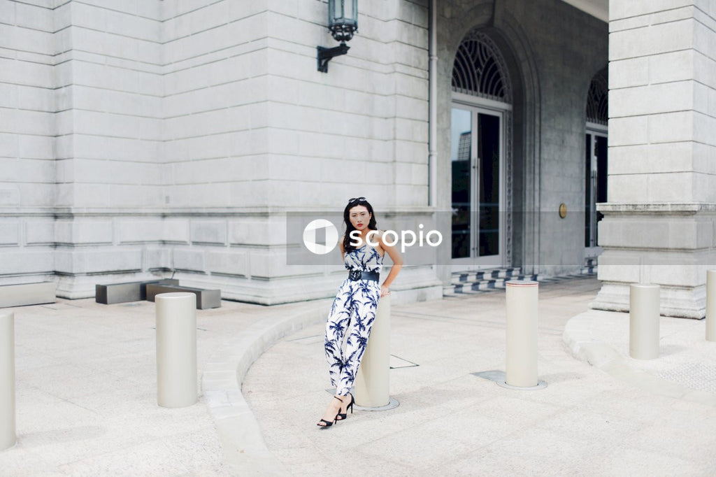 Woman in light and dark jumpsuit posing in front of building