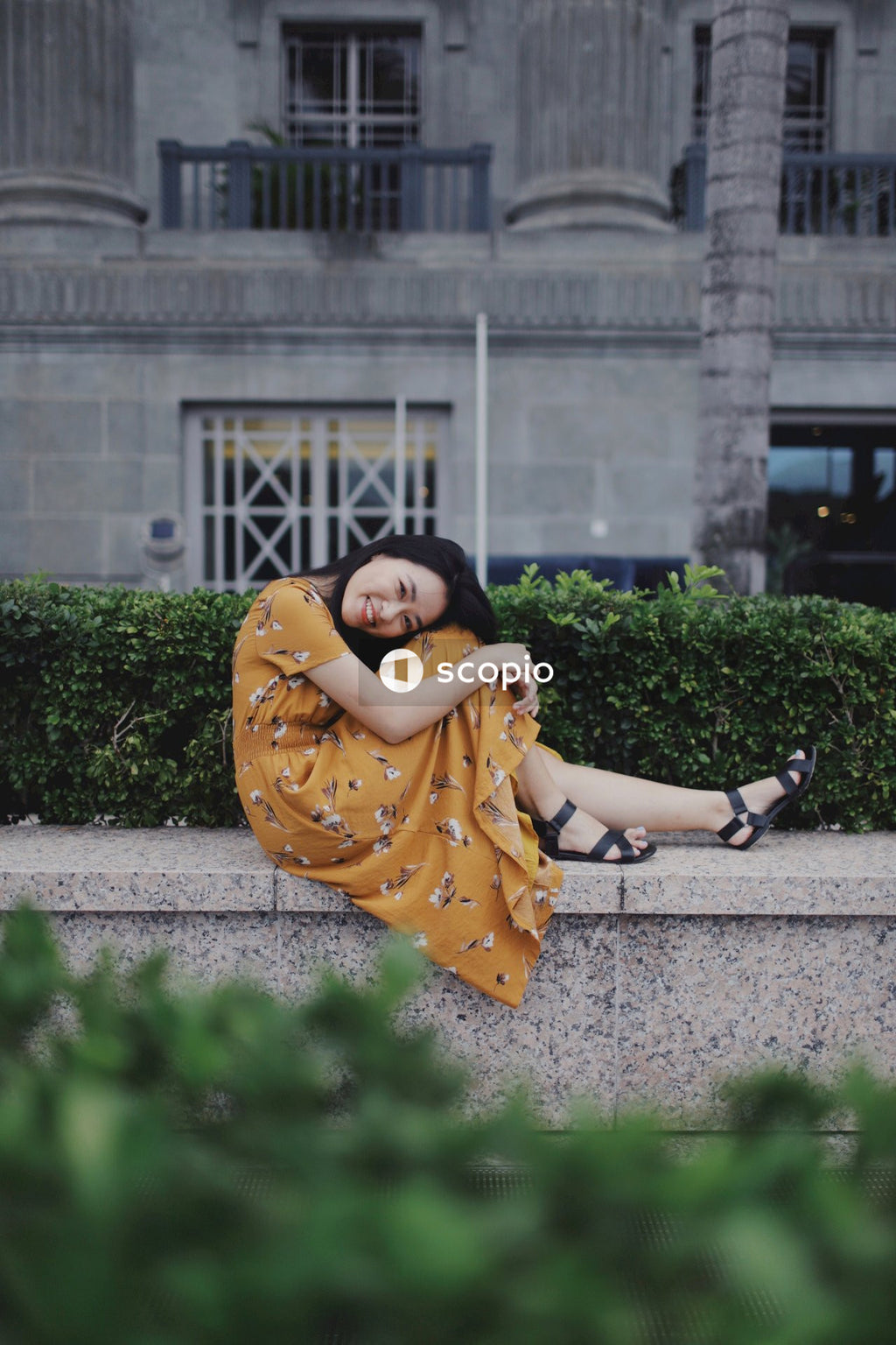Woman in long orange dress sitting on concrete bench