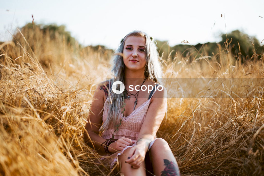 Woman in brown tank top sitting on brown grass field