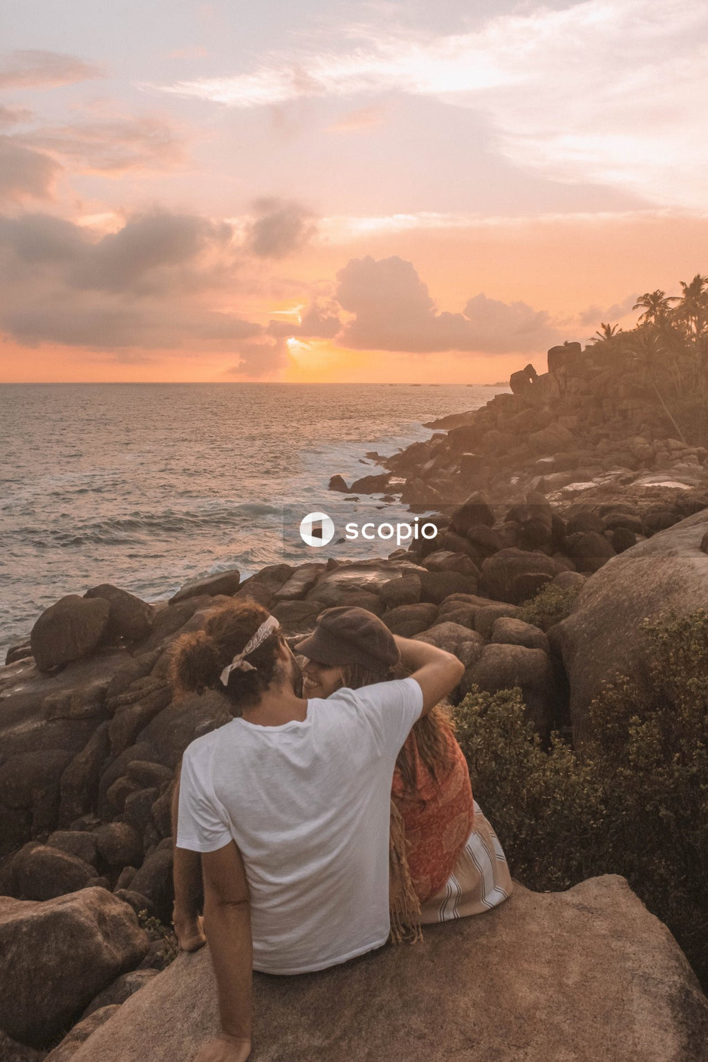 Man and woman hugging in front of ocean view during sunset