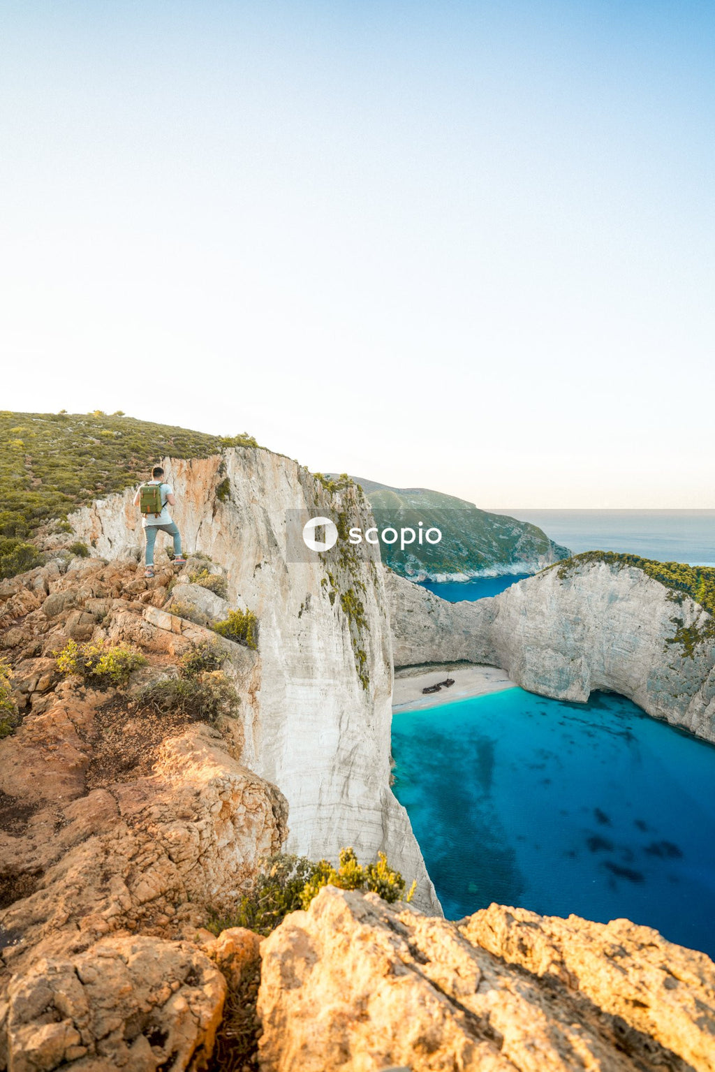 Brown and green cliff near blue sea under white sky