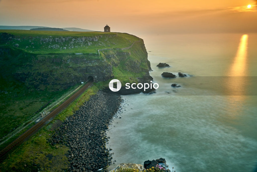 House on cliff viewing sea under orange sky
