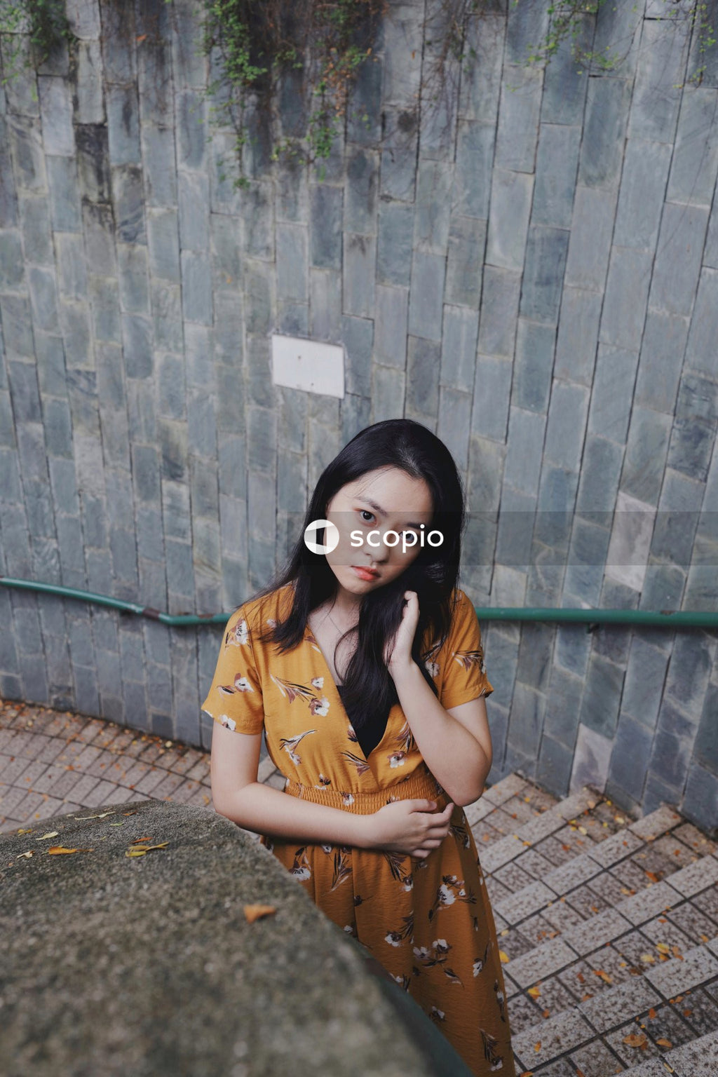 Asian woman in orange dress standing on stairs