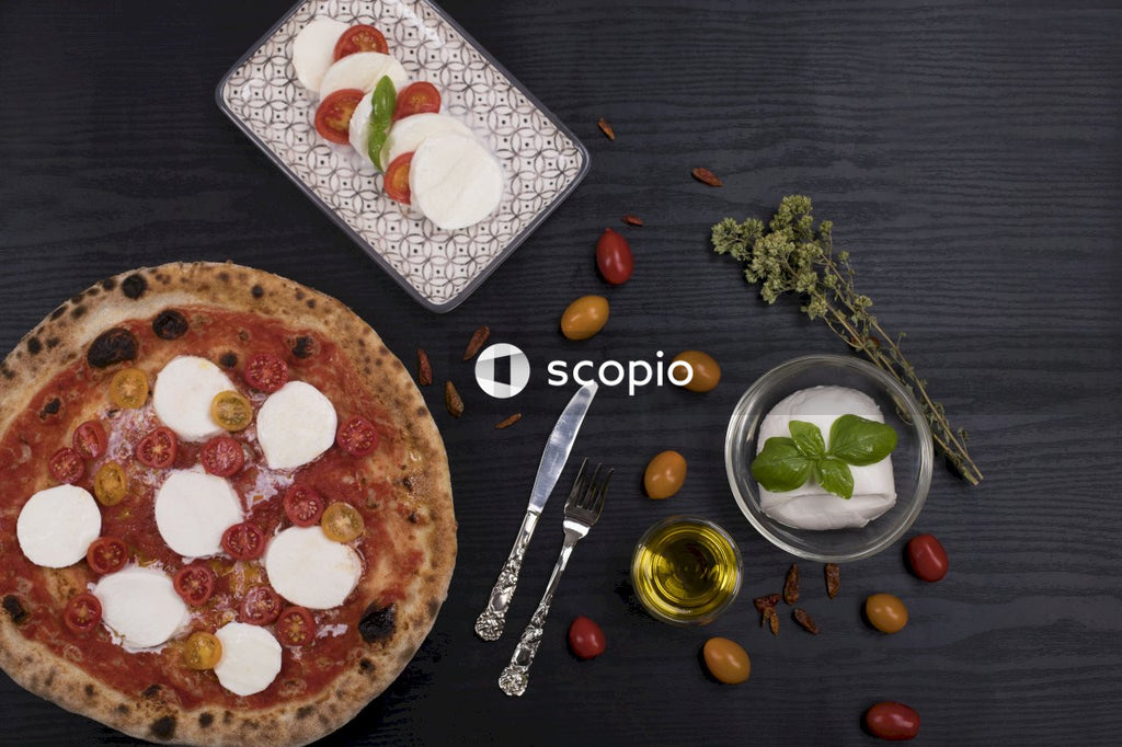 Pizza on white ceramic plate beside stainless steel fork and knife