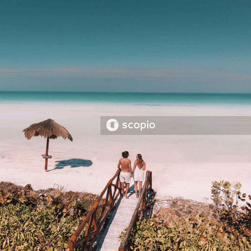 Man and woman holding hands on dock facing the ocean