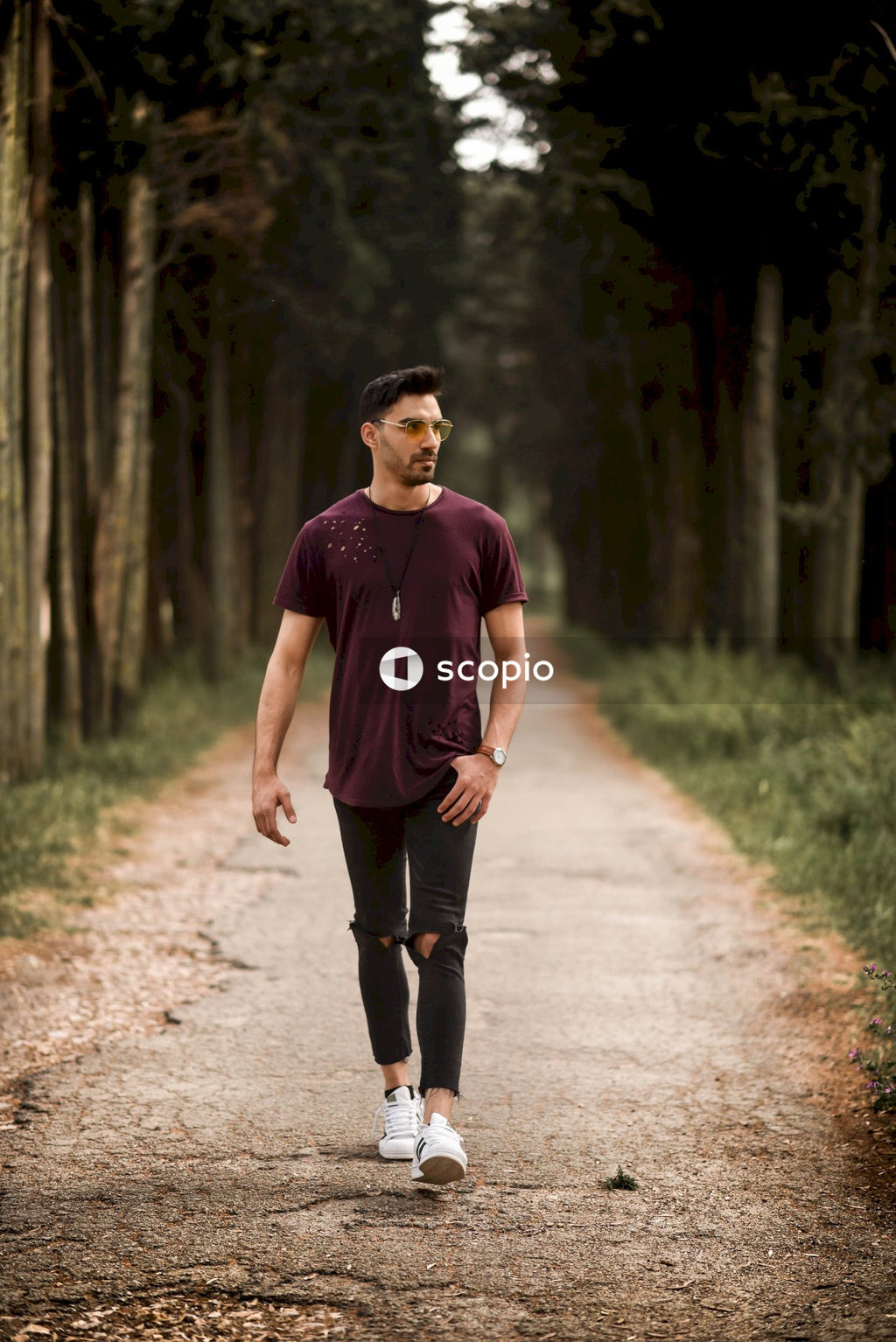 Man in purple t-shirt walking on pathway near trees